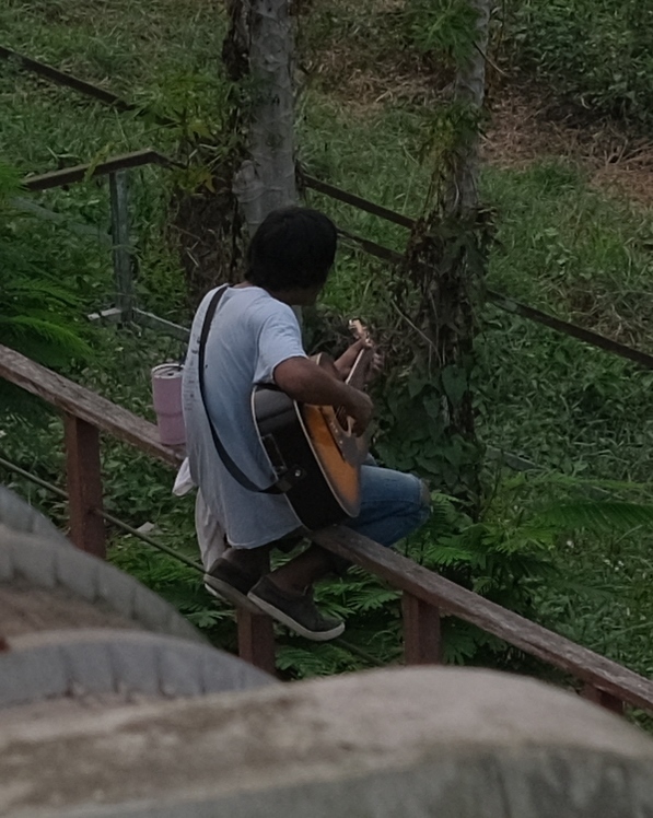 ギターを弾きながら歌っています．．．かなり上手．．．翌日の午後6時から歩行者天国）で歌っていました、前にはチップ箱があり。