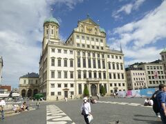 今日はマクシミリアン通りを歩くこと、市庁舎の黄金の間（改装なったと聞く）を見る事、Fuggereiフッゲライを訪ねる事に絞った。

⑤Rathaus市庁舎：
市庁舎広場に立つ、アウクスブルクで最も重要な建築（1615~20年）。
ドイツルネサンスの傑作と云われている。
3階の黄金の広間は今日のハイライトだ。昔の市庁舎、職人の仕事の歴史などを天井や周囲の壁に描いて、それは見事なものだ。
15：50～16：15　入場券Euro4。

⑥アウグストゥスの噴水（1594年）。

⑦Perlachturmペルラッハ塔：市庁舎の左手に隣接した塔は1182年完工。高さ70m。

写真はアウクスブルクの市庁舎：アウクスブルクを象徴する建物である。