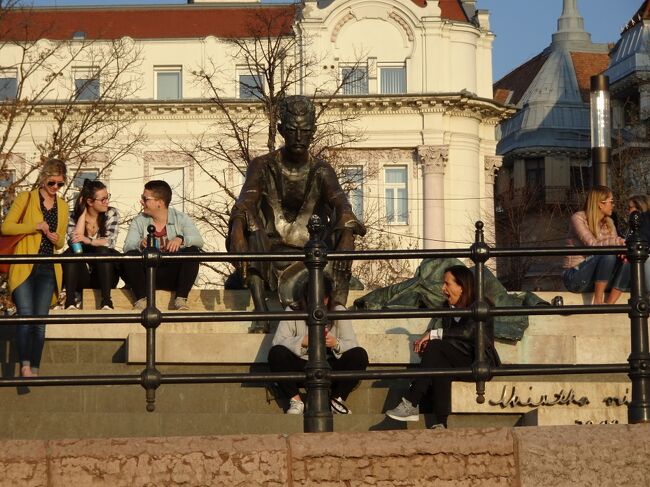 Attila József Statue<br />József Attila-szobor<br /><br />ん、でかい人が座っていると思ったら、銅像でした。<br /><br />ヨージェフ・アティッラ (József Attila, 1905年4月11日 ? 1937年12月3日)は、ハンガリーの詩人。綴りからヨージェフ・アッティラとも表記される場合もあるが、Attila の実際の発音はアッティラではなく、アティッラである。なお、姓のヨージェフも普通に男性名として使われるため、ハンガリーでは彼の名前を姓だけでヨージェフと呼ぶことはなく、必ずヨージェフ・アティッラと姓名で呼ぶのが習わしである。<br />1905年にハンガリーのブダペストで生まれる。父はバナト地方のフェーレジハーズ村の出身で、石鹸工場の労働者、母はハンガリー大平原のサバドサーッラーシュ市生まれの農家出身であり、のちにブダペストで洗濯女になった。3歳で父が蒸発。14歳の時に母は死去。高校在学中、17歳で初の詩集『A szépség koldusa』を発表する。高校卒業後、南ハンガリーのセゲド市のフェレンツ・ヨージェフ大学に入学。1925年に2作目の詩集『Nem én kiáltok』を発表するが、一部の詩の内容から大学を除籍される。その後、ウィーンに行き、それから1926年から1927年までパリに滞在、ソルボンヌで学ぶ。フランス文学を耽読し、特にフランソワ・ヴィヨンの詩に惹かれ、ハンガリー語に翻訳した。また、ヘーゲルやマルクスを読み、影響を受ける。ハンガリーに帰国後、3作目の詩集『Nincsen apám se anyám』を発表した。1930年、ハンガリー共産党に入党するが、1934年に党を除籍される。文芸誌『Szép Szó』を旗揚げするが、いつしか精神疾患にかかり、病院で精神科医から治療を受ける。1936年に最後の詩集『Nagyon fáj』を発表。1937年、ハンガリーのバラトン湖近くの村バラトンサールソーで鉄道の線路上に飛び込み自殺。(wikiより)
