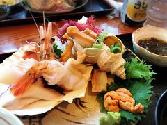 ウトロへの到着は11：30。
早朝便だったので、朝は空港で食べた菓子パン少々だけだったのでもうお腹が空きまくり。

この日は羅臼岳や羅臼湖、知床五湖のトレッキング情報を入手するために、知床自然センター（ビジターセンター）へ行くのが第一目的だが、腹は減ってはなんとやらで、まずは腹ごしらえ。

ウトロの道の駅の向かい側にある“荒磯料理熊の家”へ。
せっかくなので知床の海の幸を詰め込んだ刺身定食（1950円）をいただく。
丸々1匹分のツブ貝にホタテ、タコ、ソイにバフンウニ。
“ソイ”は白身の魚で本州のスーパーでは見かけることのない魚で、鯛の漁獲量の少ない北海道では鯛の代替品として食され、別名を“北海道の鯛”といわれている。

食べた感想は鯛と比べるとコリコリの食感は劣るが、淡泊な白身の中に旨味がある魚だった。
