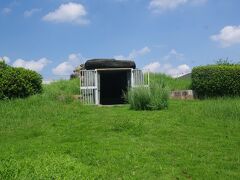 次いで、行田市藤原町の富士見工業団地内の八幡山公園一角を占める八幡山古墳（同町1-26-12）です。若小玉古墳群の一角にある本古墳は７世紀前半の築造と推定されており、かつては墳丘で覆われていましたが、1934年の小針沼干拓で墳丘が崩されて石室が露出しました。1977～9年にかけて石室の復原がなされて現在に至っています。本古墳は発掘調査により本来は直径80ｍの円墳で、周溝は存在しないと考えられています。写真は正面から見た本古墳で、石室が露出していることがお分かりでしょう。扉が開いているように、石室内は見学ができ、公開時間は10～6時（土・日・祝日）です。