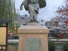 出雲の阿国像
鴨川に架かる四条大橋のたもとに像と説明板が建っています。1603年に四条河原でかぶきをどりを披露、都人に喝采を浴び、現在の歌舞伎の基を作ったそうです。江戸時代に女歌舞伎が禁止になり、男が女形を演じるようになったため、その後の阿国の消息ははっきりしないようです。謎に包まれている人物のようですが、歌舞伎の基礎を作った人物であることは間違いないようで、像も歌舞伎が演じられる南座に向かって建っています。
