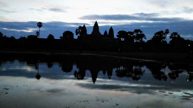 だんだんと明るくなってアンコールワットのシルエットが暗闇から浮かび上がってくる。<br />雲がたなびいているので真っ赤にはならないが、幻想的な景色。