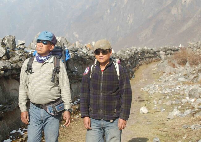 ほどなく進むとマニ石が並ぶ<br />まるで中央分離帯のようでもあり<br />万里の長城のようでもある　石には経文が彫りこまれている<br />左はリーダー(ｻｰﾀﾞ-)のゴレさん、右はコックのプラディップさん<br />プラディップ氏はゴーキョで一緒でした。川谷拓三そっくり