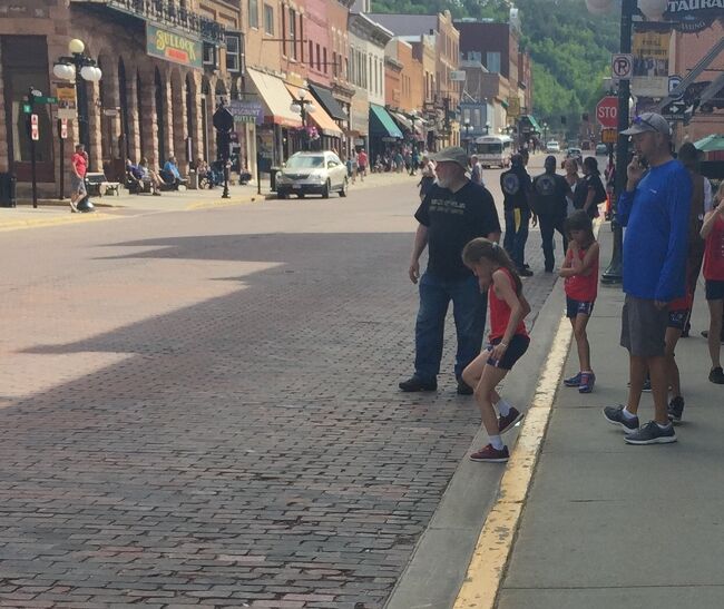 石畳の車道を前に子供たちがハシャいでいます。