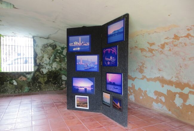 コーンウォリス要塞の展示室の室内光景と、先程とは異なる展示パネルの紹介です。2枚組の衝立風の展示パネルには、説明文なしで9枚の写真が展示されていました。マラッカ海峡の風景写真と、ペナン島の街や建物の光景でした。(同上)