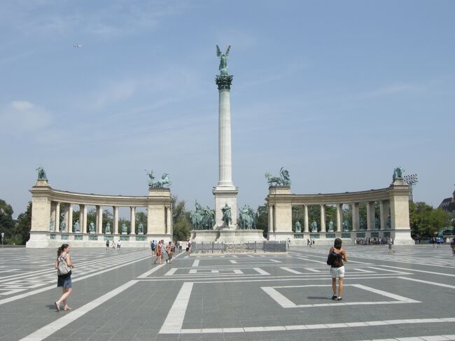 アンドラーシ通りの突き当りに広大な市民公園があり、<br />その中に「英雄広場」がある。<br />二重帝国時代の19世紀末に建国1000年を記念して建設された広場だ。<br /><br />半円形の建物に、ハンガリーの英雄（国王や政治家）14人の銅像が並んでいる。<br />一番左が初代イシュトバーン像。<br />中央にはオベリスクのような高い尖塔が建ち<br />一番上には大天使ガブリエルが二重十字と王冠を掲げて立っている。