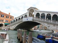 歩いて名所へ。

「リアルト橋 Ponte di Rialto：
カナル グランデ（大運河）に架かる4つの橋（リアルト橋、スカルツィ橋、アッカデミア橋、コスティトゥツィオーネ橋）の中で最も有名な橋。初期のころは木製の跳ね橋でしたが耐久性などに問題があり、1557年設計案を一般公募し、ミケランジェロを差し置いてアントニオ・ダ・ポンテの設計が採用され、石造りの橋が完成しました」

「橋の下を船が通れるように造られた長さ48m、幅22m、水面からの高さ7.5mの太鼓橋で、橋の上にはアーケードが造られ、商店があるほど大きなものです。そのため「白い巨象」とも呼ばれています。1987年「ベネチアとその潟」として世界遺産にも登録されました」