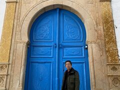 チュニジアンブルーの扉の前でポーズ