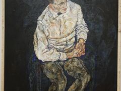 エゴン・シーレ「カール･グリュンヴァルトの肖像 」1917年 豊田美術館
エゴン･シーレは、人間の実在とその表現に取り組んだ画家の一人です。虚飾をそぎ落と した鋭く力強いデッサンと渋みのある色彩によって、人間の内面まで浮き彫りにしようと しました。 しっかりと組み合わせた両手と、落ち着いた表情が印象的な肖像画です。モデルが腰を掛 けている椅子は暗い背景に溶け込むように描かれ、人物そのもの存在が際立って見えます。 シーレはさまざまな角度からのデッサンを行い、最終的にはモデルを正面からではなく俯 瞰するような視点から描きました。シーレはこの作品を描いた１年後、28歳の短い生涯を 閉じます。 グリュンヴァルトは繊維業を営む美術愛好家であり、第一次大戦中のシーレ兵役時には上 官、後にはパトロン（後援者）にもなった人物です。
※ 本展での撮影ではありません（豊田美術館での撮影）