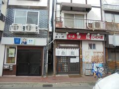 そして目当ての白龍本店
じゃじゃ麺の老舗名店ですがここはなんと9:00から営業されてる･･･はず･･･という情報だったのですが、開いてないように見える。
この通り、飲食店が建ち並んでいますが周囲もまだ開いているお店は無く、そのせいもあって開いてないように見えました。ここまで来たのに、どうしよう･･･と落胆しつつ、できる事は全部しようとダメ元でドアを開けたら･･･開きました。