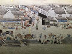 フォーシーズンズホテル東京大手町にチェックインすべく，三越前から大手町に戻ります。

写真は，三越前駅コンコース展示，『熈代勝覧（きだいしょうらん）』のリプロダクション。
https://nihonbashi-info.tokyo/kidaishoran/
1805年頃の江戸・日本橋界隈の日常生活を克明に描いた紙本着色絵巻（作者不詳），ベルリン国立アジア美術館所蔵。1999年発見，1995年以前の経緯不明。

写真の部分には，画面右から，琵琶法師，茶碗売り，雪駄直し，辻占（つじうら←金箔で付された地名「通白銀町」の上，犬の右側），子守，菓子の立売，刃物研ぎなどの姿が生き生きと描かれている。面白いね。