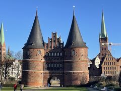 リューベック中央駅（Lübeck Hbf）から徒歩約10分。

かつて星状に築かれていた城壁跡に残るお堀を越え、トラヴェ川の手前に堂々と立つのがホルステン門と右手に続く塩の倉庫。

1987年に世界文化遺産登録された「ハンザ同盟都市リューベック」への入り口です。

あれ？ホルステン門が傾いて見えませんか？
実は、傾いています。15世紀に建設した際、街を強固に守るため門を頑丈にしすぎた結果、重みで地盤沈下してしまったそう・・・

中は博物館になっていて、入れます。

門の奥、左右に見える尖塔が素敵ですよね。
向かって左側がマリエン教会の二つの塔、右側が聖ペトリ教会の塔です。