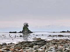 "富山湾越しに見られる立山連峰"の絶景が見たくて、海岸まで来てみました。女岩はくっきり見えたのですが、お天気が良くなくて立山連峰がうっすらとしか見えませんでした。

冠雪した立山連峰がくっきりよく見える条件は「空気が澄んでいて霞みが少ない冬のよく晴れた日」（11月～3月頃）なんだとか。

ちなみに、周囲約80 mの小さな島である"女岩"は、周囲の小さな岩が母親とたくさんの子供のように見えることから「女岩」と呼ばれるようになったということです。