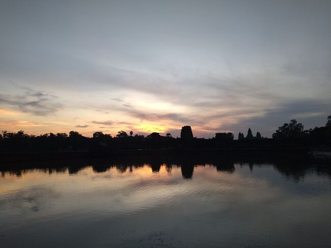 定刻通りホテル出発。バスで移動して、ガイドのポリンさんから、アンコールワットベストの朝日撮影スポットと案内されたのは外濠。<br /><br />この時期は、寺院内に入ると綺麗な写真は撮れないとのことでした。<br /><br />外濠に腰を降ろし、朝日が上がるのを待ちます。<br />