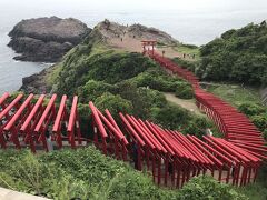 絶景スポット「元乃隅神社」。
1987年（昭和62年）から10年間かけて奉納された123基の赤い鳥居。鳥居は100ｍ以上にわたって並び、海と岩場のコントラストは絶景。

駐車場は有料、300円。
元乃隅神社までの道路は狭く一方通行。ここも休日には駐車場待ちの渋滞が発生するようだが、11時20分頃到着するが5分程の待ち時間だけで駐車できた。

