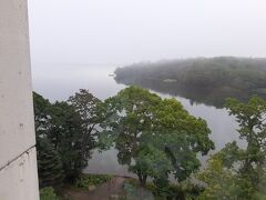 おはようございます。　　　窓からの景色。　　湖の見える部屋指定ですが、左のコンクリートがジャマです。　　　霧が出ています。
