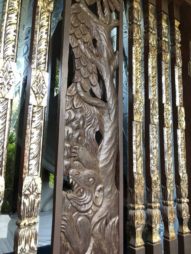 私にしては高級な1泊Rp.985,000<br /><br />たぶんね、南部はすっきりビルディングタイプのホテルの方がコスパがいいんだろうけど、私は、木や花がいっぱいあってバリらしい老舗宿に泊まりたかった。<br /><br />前回泊まったPoppies Bali Hotelがとても好きになったんだけど、あのあたりは渋滞がひどすぎておススメできないと、在住の友人にアドバイスもらったので、今回はここに。<br /><br />扉は木の観音開き、南京錠で鍵をかけるタイプ。<br />窓の外側にもこんな木彫りが。<br />うれしい。