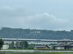 新幹線の黒部駅越しの宮の運動公園。公園現地では見ることのできない大きな看板の『名水の里　黒部』。