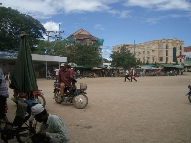 タイの出国手続きを済ませ、いよいよカンボジアのImmigrationへ。<br />Immigrationまでは小さな車（？）で移動。乗車時間約２分。<br />ベンチに座って入国書類を記入していると、急に悲鳴が･･･・。<br />「何？　何？　何？」<br />後方から鼠が全力疾走。<br />「うわ！！」<br />咄嗟に足をベンチの上に避難。<br />「これがカンボジアかァ･･･。こんなんで驚いてちゃダメだ。」<br /><br />鼠騒動は一件落着。入国手続きもスムーズに終了。<br />全員が無事通過するまでしばし待機。しかし暑い。。。<br />ここからの長旅に備え、売店で水を購入する。売っているのは１２，３歳の女の子。<br />（左がImmigration通過後に撮った写真）<br />ようやく全員そろったので、仮のバスに乗り込みバスターミナル（ただの空き地）へ。そこからゲストハウス（以下GH）行きのバスに乗り換える。<br />ここはもうタイではない。コンクリートの道なんて存在しない。<br />露店が並ぶ赤土のでこぼこ道をバスはひたすら走ること５分。<br /><br />１５：１５　バス乗り換え。<br />待っていたのは日本のどっかのレストランが使っていた送迎バス。（右の写真をよく見ると分かる。）<br />ガイドさんとはここでお別れ。代わりに最終目的地のGHの人がバスに乗る。<br />一人身＆荷物の少ない私は早めに乗って窓際の席をゲット。<br />最終的には補助席まで使って２０人程の人で車内は埋め尽くされる。<br />GHの人は座れないのでドア付近に立ったまま。<br />「この人、あと５時間も立つの？」<br /><br />ここからが悪路本番。<br />『バスはジャンプするので頭上注意』と聞いていたので、かなり覚悟を決める。そして酔い止めも服用。<br /><br />ガタガタ音をたてゴミだらけの道をバスは行く。<br />『この道を行けばどうなるものか･･･。危ぶむなかれ･･･。』<br />進むしか選択肢はない。<br />しばらくすると道の両脇に民家が。<br />やしの葉でできた屋根、ドアのない家、ハンモックで寝る人、そして裸足の子供。<br />教科書やテレビの中の世界に今私はいる。<br />一秒でも無駄にしたくない、全てを目に焼き付けるんだ（＆酔い防止の為）と窓を全開に。<br /><br />・・・途中、旅行客を乗せたまま故障したバスとすれ違う。明日はわが身。<br /><br />１７：１５　休憩ポイント（写真中央・右）<br />初カンボジアトイレ。・・・汚い。<br />水洗なだけまだマシ。が･･･、壊れていたので流れなかった･･･。知らん顔でそのまんま。<br /><br />トイレの向こう側の柵から子供が手を出している。<br />「これからどれだけこんな光景に出会うのだろう。」胸が痛くなった。<br /><br />初トイレの後、手洗い場にあった鏡に自分の顔が映った。<br />「人種変わってるし･･･。」<br />髪の毛を触ると手は茶色くなるし、顔は茶色。<br />ビオレの顔用シートでふき取ると真っ茶色。<br />いくらメイクしても無駄。化粧直しもせずバスへ。<br /><br />相変わらずのでこぼこ道だが、バスは順調に走る。<br />辺りも暗くなってきた。<br /><br />トラブル発生！！！バスが止まった！！<br />「えっ、ここで･･･。マジ？？　周り草原しかないんですけど･･･。」<br />ここで夜を明かす私達の姿が頭を過ぎる。<br />運転手とGHの人がバスの外に出て何かしている。<br />会話は英語ではないので分からない。<br />多分５分も経っていないと思うが、バス復活。<br />「良かったァ。」<br />後から聞いた話：カンボジアで会った日本人の女の子が乗って来たバスは途中で動かなくなり、男性陣が押したらしい。<br />それを考えると、私達は限りなくラッキー。<br /><br />１９：３０　売店でトイレ休憩。汚れた車の洗車タイム。<br />ここでも小さな子供が物を売ってくる。時には着けてるアクセサリーを引っ張る。（私は何もしてなかったので無事）<br />少し大きい女の子はどこで覚えたのか、恐らく前に来た日本人から教わったと思うが、『宮迫です。』を披露。<br /><br />バスは更に走る。<br />もう暗いし、これ以上汚れたくないので、何度も窓を閉めるのだが、振動で何度も開く。<br />さすがにこんなに長時間移動すると疲れる。こんな悪環境でもウトウトできる図太い人間に変身。<br />ふと気がつくといつも窓が開いている。その度に閉める、この繰り返し。<br /><br />２１：１０　GHに到着<br />「日本人、日本人。」（このバスには私も含め日本人が多かった。）の歓声に包まれようやくバスから降りられる。<br />他に行く当てもないので、そのままチェックイン。<br /><br /><br />『国境越えカンボジア編』でした。