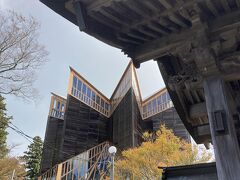 境内を登っていくと、ガラスに囲まれた近代的な建物がありました。
1998年完成の信徒会館、「星嶺」と名付けられている、大舞台を持つ木とガラスの殿堂で、参詣者の心のふれ合いの場として建てられたもののようです。

最上部にある礼拝堂は、杉丸太16本で支えられていて、中空に「矢筈」の立体的なモチーフが浮遊する象徴的なデザインとなっています。
中の円形フロアーは、2層となった透明なガラス床に、中央と天井に「矢筈」の紋章が施され、本尊の世界感を体感できる新しい宗教空間として注目されているようですが、一般参詣者は入館できないそうです。

設計は高松 伸 氏で、星と能勢家の家紋の矢筈がモチーフになっているようです。
1999年BCS賞を受賞しています。