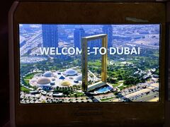 シートモニターの画面には「WELCOME TO DUBAI」のメッセージと
2018年1月1日にオープンした金色の額縁を模したデザインの
『ドバイフレーム（Dubai Frame）』の映像が映し出されました。

金色の額縁を模したデザインの超高層ビル『ドバイフレーム』は、
全長150mの2つのタワーに93mの橋が渡されている構造です。
展望フロアの「スカイデッキ」からは、パノラマの展望が広がり、
南側には高さ828mの超高層ビル『ブルジュ・ハリファ』がそびえる
ニュー・ドバイと、北側には旧市街のオールド・ドバイの2つの異なる
眺望を楽しむことができます。

ちなみに、『ドバイフレーム』は2019年5月には
「額縁の形をした世界最大の建造物」としてギネス世界記録に
登録されたことでも知られています。あとで載せますがめちゃ大きい！