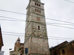 大聖堂に隣接して建っている塔（鐘楼）がトッレ・チヴィカ（市民の塔）。世界遺産の構成資産です。
大聖堂と同じくランフランコの設計で1179年ロマネスク様式で５階部分まで建てられた。
1319年にアッリゴ・ダ・カンピオーネの設計でゴシック様式の八角形の尖塔が追加されました。この先頭部分に花冠状の装飾（ギルランダ）があることから「ギルランディーナの塔」と呼ばれるようになりました。塔の高さは89・32ｍ、尖塔は37ｍです。この塔、市民の塔の時代は5階建てだったそうですが外かろ見ると６階建てに見えます。後で付けられたゴシック様式の尖塔は八角形なのでどう見ても６階建てです。
そこでハタと気づきました。日本では６階建てでも欧州では５階建てなんです。日本の１階は欧州では０階でした。
塔の前にある銅像は作家で詩人のアレッサンドロ・タッソーニ。