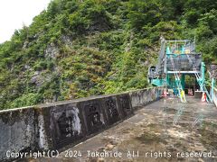 白岩砂防堰堤

主堰堤は高さ63m、７基の副堰堤を併せると高さ108mとなる落差日本一の砂防堰堤で重要文化財に指定されています。
奥の斜面の中にアンカーやケーブルボルトを埋めて岩盤の崩落対策を施しています。
崖を構成する白い花崗岩から白岩の名前が付けられました。
ここで往路がバス、復路がトロッコの別班と入れ替わってバスに乗車します。


白岩砂防堰堤：https://www.hrr.mlit.go.jp/tateyama/jigyo/shisetsu/shiraiwa.html
白岩砂防堰堤：https://ja.wikipedia.org/wiki/%E7%99%BD%E5%B2%A9%E5%A0%B0%E5%A0%A4
重要文化財：https://bunka.nii.ac.jp/heritages/detail/192113
崩落対策：https://www.hrr.mlit.go.jp/tateyama/jigyo/techno.html