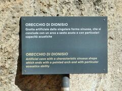 有名な｢ディオニュシオスの耳(Orecchio di Dionisio)｣の入口にある説明板。
｢ディオニュシオスの耳　尖ったアーチで終わる特徴的な曲がりくねった形状と特別な音響能力を備えた人工洞窟(Google翻訳)｣
『「この短刀で何をするつもりであったか。言え！」暴君ディオニスは静かに、けれども威厳を以って問いつめた。』(青空文庫より)
ディオニュシオス1世は『走れメロス』に出てくる「暴君ディオニス」のモデルと言われている。