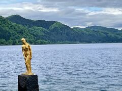 日本で最も深い湖である田沢湖の水深は423.4ｍ。
湖面が鮮やかな瑠璃・碧・藍と変化する様は一見の価値ありだとか。
風が強く、曇天だったので、鮮やかな湖面とは言えないけれど

●たつこ像の逸話
その昔、美貌を永遠のものにと望んだ辰子という娘がいつしか龍と化してしまい、田沢湖に身を投じたという伝説から建てられました。
この伝説には続きがあり、八郎潟という湖にも、やはり人間から龍へと姿を変えられた八郎太郎という男がおり、辰子と愛し合うようになったという。
2人が共に田沢湖に暮らすようになったために、田沢湖は冬も凍ることなくますます深くなり、一方で主がいなくなった八郎潟は年を追うごとに浅くなったとか。

●何故に金色?　たつこ像に、違和感。
湖のシンボルとして昭和43(1968)年4月12日に田沢湖畔潟尻に完成した高さ2.3mのブロンズ像。
表面を金箔漆塗り仕上げとしたのは、酸性の強い湖水からの腐食に耐性を持たせるため。
作者は岩手県出身で当時東京芸術大学教授で彫刻家の舟越保武氏
