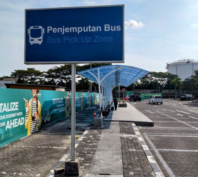 バス停は、店舗群を抜けてタクシー乗りの勧誘がなされる先の左側。<br />立体式駐車場前の前にPenjemputan Busの標識があった。<br />誰もバス停にはいなかったが、10分ほどでバスが来た。
