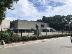 《国立西洋美術館》外観…「国立西洋美術館」の建築様式は、「ピロティ」（高床）構造となっています。従来の建物は、石やレンガを　　　積み上げて壁を造ることで建物を支えていましたが、この「国立西洋美術館」は鉄筋コンクリート製の柱と床板で建物を支えています。そして、「国立西洋美術館」の正面の「本館外壁」には緑色の玉石が埋め込まれたパネルが使用されています。遠くから見るとまさにグリーンウォールで公園内の緑や紅葉の時期でも周囲に溶け込むような調和が感じられ、また、近づいてみることで玉石が敷き詰められているのが確認できます。