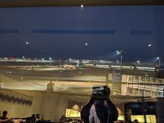 ２０２４年６月２９日夜、昨年、金曜日の夜に利用した際は、ANAラウンジは、旅客でごった返しており、座る場所を確保するのにも苦労する有り様。今年は、土曜日の夜とあって、ラウンジは、閑散と言っていいほどに空いている。窓から見える空港のグラウンドも行き交う地上の車両ものんびりとした感じ。その景色を移したら、偶然にも、下半分に、ラウンジ内が反射して映り込んでいた。