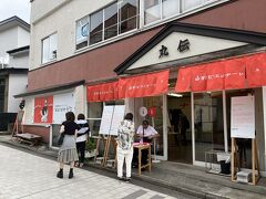 『山形ビエンナーレ』と書かれた赤い暖簾が吊るされた『丸伝』さんの前を通りました。

丸伝さんは蔵王温泉に伝わる郷土菓子『稲花（いが）餅』を製造・販売されるお店ですが、この時は店舗丸ごと会場になっていて臨時休業されていました。