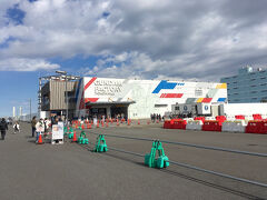 埠頭の一角がガンダムファクトリーヨコハマになっていました。
白い建屋の壁に赤、青、黄色とガンダムのカラーリングが入っていました。
施設前でネットで購入していたチケットをスマホで提示して、中に入りました。
