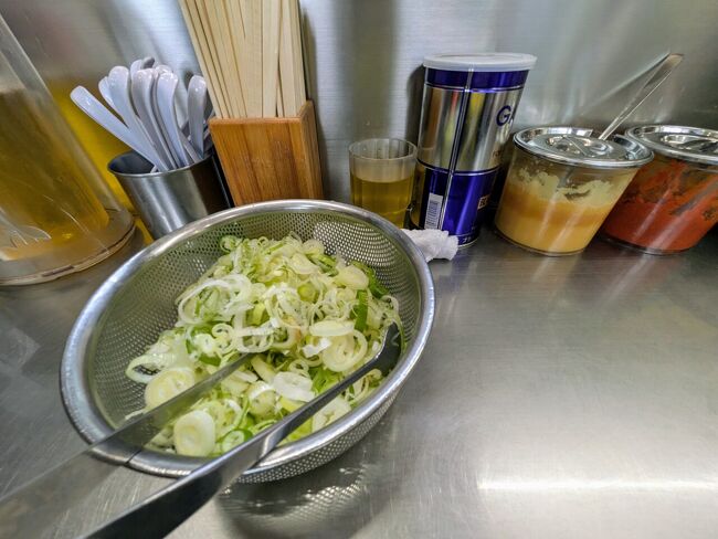 カウンターに常備されたネギは入れ放題♪だが、ネギは好きなのに、食べすぎると喉が渇くから・・・と、夫はほどほどにする。