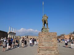 「Foro」(フォロ)
フォロはラテン語でForum(フォルム)のこと。フォーラムと同じ語源で、公共の広場を示す。昔はポンペイの公共的な建物、神殿とか市場とか裁判所が集まっていた。今もポンペイ遺跡の中心で、多くの観光客が集まっている。

遠くに霞むのが、ヴェスヴィオ火山。噴火は西暦79年に起こり、1昼夜に渡り火山灰が降った後、大規模な火砕流により街ごと埋まってしまった。街と共に多くの逃げ遅れた人も埋もれている。
噴火の後、この地に町ができることはなかったが、地下に町が埋まっていることは、ある程度知られていたようだ。本格的な発掘が始まったのは18世紀からで、相方が大好きなモーツァルトも、ここを訪れているよ。