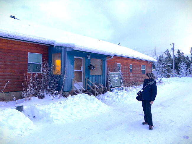 犬ぞりの日は、10：45に宿泊しているカレイドロッジを出発した。<br />アクティビティの行われる犬舎までは車で15分くらい。<br />往復の送迎はカレイドロッジのスタッフが担当してくれる。<br /><br />日本で10:45と言えばどの季節でも太陽が昇った日中の時間帯だが、極北エリアではその常識は通用しない。<br />ホワイトホースでは冬至付近の日の出が朝11時頃なので正確に表現するならば、10:45は日の出前の時刻となる。<br /><br />だから、外は薄暮。<br />朝焼けすら見えない、空気も凍り付く様な寒さの朝だった。<br />11時を朝と表現するのも変な気はするが、夜明けを朝と解釈するならば、朝だろう。<br />