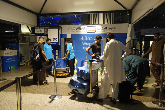 さて、出発ロビー入り口にはこんな御商売が店開き。<br />手荷物の「梱包」屋さんです。<br />深夜でも大繁盛な様子ですが、