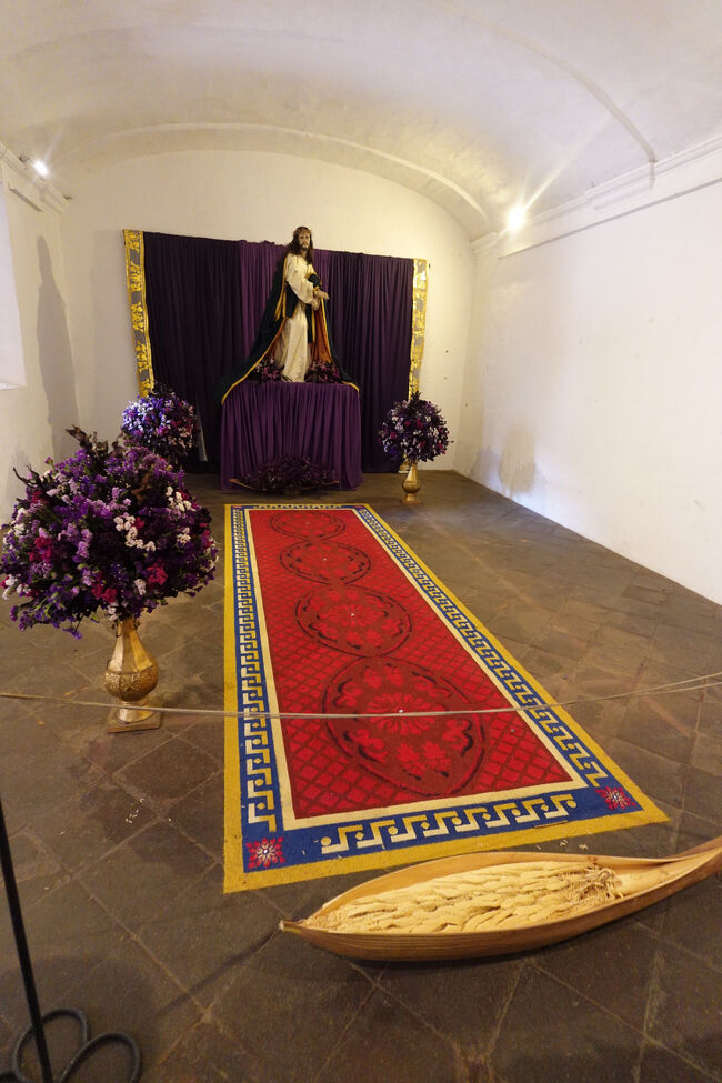 花の絨毯（おがくずで出来ている。この上に野菜などを乗せ、山車に乗せ、ゆっくりと繰り出します。イエスの死後までこの行事は行う。）