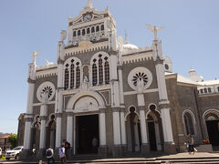 ロス・アンヘルス大聖堂（左にコスタリカ　右にバチカンの旗）地震で崩壊。１６３５年８月２日に奇跡の黒いマリア像がここで発見された。１６７５年にこの奇跡の像を安置する為に聖堂を建設。地震で何度か崩壊したが、１９２６年に再建された。８月２日の聖日には１００－２００万人の巡礼者が来る。裏の地下聖堂（聖母像が発見された所）へ来ます。