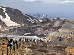 リフトから降りるとそこは大自然。
展望台は遥か遠くに見える。軽装なため寒くて辿り着けそうにない。
展望台より手前にもお釜が見えるスポットがあるらしく人が集まっていたのでそこを目指す。
エメラルドグリーンのお釜を創造していたけど、見えたのはちょっと違う姿。GW頃はお釜の水面が凍っているためこのような景色になっているらしい。これはこれで貴重な姿なんだな。