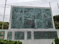 通りすがりに見かけた石碑　日本海海戦紀念碑でした。
対馬沖では1905年（明治38年）の5月27～28日にかけて大日本帝国海軍とロシアのバルチック艦隊による日本海海戦が行われました。
この海戦の際、撃沈されたロシアバルチック艦隊のウラジミル・モノマフ号の水兵143名は、4隻のボートに分乗し、この地に上陸しました。
戦況を見守る傍ら農作業をしていた農婦は、命からがら逃げ延びてきたこの水兵達を水の湧き出す泉へ案内し、夜は西泊の民家へ分宿させるなど、手厚く持てなしたといいます。
レリーフに描かれているシーンは、ロシア軍提督のロゼストベンスキーを東郷平八郎が見舞っている場面です。東郷元帥の後ろにいるには秋山真之です。「友好」「平和」の文字が刻まれています。