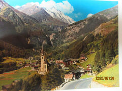 「St.Vinzenz聖ヴィンツェンツ教会＞

Heiligenblutハイリゲンブルートはドイツ語で「Heiligen聖なるblut血」という意味である。また、キリスト教で「聖なる血」とは「キリストが磔刑された際に流された血」のことで、聖遺物として信仰の対象となっている。

伝説によると、10世紀頃、この地で雪崩に巻き込まれて行き倒れた男が発見されました。
行き倒れた男はビザンチン（東ローマ）帝国（首都Konstantinopelコンスタンティノープル、後のイスタンブール）のBriccius ブリッチウスで、彼は（コンスタンチノーブルに保管されていた）「聖なる血」＝「聖遺物」をアルプスの北の国々（デンマーク？！）にもたらそうと旅をしていた。
村人の手により、ブリッチウスの墓と聖なる血を納める聖ヴィンツェンツ教会が建てられ、村の名を「ハイリゲンブルート＝聖なる血」と名付けました。
その後、ハイリゲンブルートは「聖なる血」＝「聖遺物」信仰に多くの巡礼者が訪れるようになったと伝えられている。
現在でも聖遺物は教会の祭壇左側に納められているそうだ。

（尚、兵士や旅人、巡礼者の守護人とされているブリッチウスは聖人への列聖を何度か嘆願されたが、認められなかったと云う）

写真：ハイリゲンブルートの町と中心に立つ聖ヴィンツェンツ教会の絵葉書