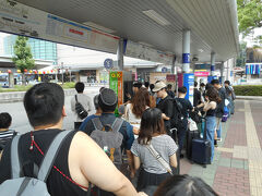 お盆休みにはいった8月9日の午前
徳島空港行きのリムジンバスを待つ人の列です。徳島空港は、到着出発に合わせて駅前からのバスが出発します。
香港行きと東京行きが１台の（正シート44席）バスに乗るようです。ざっと見て「積み残し」がありそうかなと。

5組ほどはすこし後の「路線バス」に乗られたようです（チェックインカウンターで「リムジンに積み残しが出たので、カウンタークローズを遅らせたら？」と「提案」して置きました。