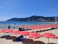 青い海と空に白い砂浜、赤いパラソルが映える。