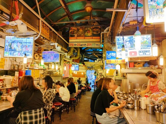 カルグクス(うどんみたいな麺料理)の屋台がたくさん軒を連ねています。<br />客引きが凄かった…夫は持っていたカバンを引き剥がされて、強制的にお店に置かれて、腕を引っ張られていた！入口付近のお店です。<br />ちょっと強引過ぎて、この店はやめようと思い、カバンを取り返して、なんとかして離れました笑<br /><br />そのお店以外も呼び込みが激しくて、「かおるTV！」って連呼していたり、「どこも同じ！」って連呼していたり笑