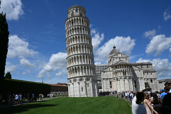 駅から10分ほど歩き、斜塔へ到着。おお、本当に傾いている。思った以上の傾きだ。周囲には斜塔を支えるような、倒すような、あるいはつまむような珍妙なポーズで写真を撮る観光客が多数おり、もちろんわれわれもその一員となった。<br />よく倒れないと感心するが、実際には倒壊のおそれもあったようで、1990年ごろから10年かけて地盤を改修し、傾きが1.5度ほど改善したという。傾きは建設中から始まっていたようで、よく見ると途中から角度が変わり、バナナ状の形になっていることがわかる。よく諦めないで完成させたものだ。