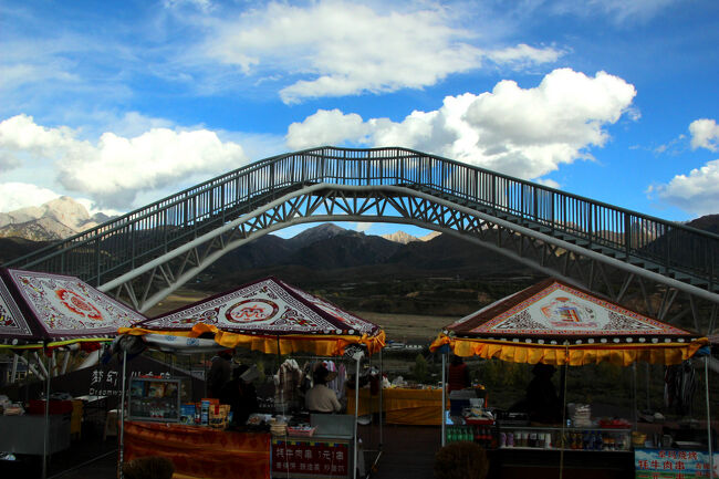 ★秋の九寨溝絶景紀行（６）～松藩県：岷山山脈<br /><br />国道が走る草原にはチベット族の小さな集落が点在し<br />テントだけの道の駅のような施設でトイレ休憩をしました。<br />テントの背後には歩道橋のような展望施設がありました。<br />テントではヤク関連のお土産などを中心に販売しています。