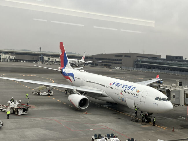 ネパール航空は成田－カトマンズ間現在週３便運行。機体の尾翼には、ネパール国旗の月と太陽があしらわれています。<br />エアバス330-200型。座席配列２－４－２です。あわよくば離陸後に富士山、着陸前にヒマラヤ山脈が見たいと、窓側ｋ席を確保しました。ネパール航空はオンラインチェックインが無く席取りは早い者勝ちなので、カウンターが7：45に開くのを待ち、１番乗り！<br />ブランケットはお願いしないと配布されません。でも機内の室温は高めで、ブランケット無しでも大丈夫だったかも。